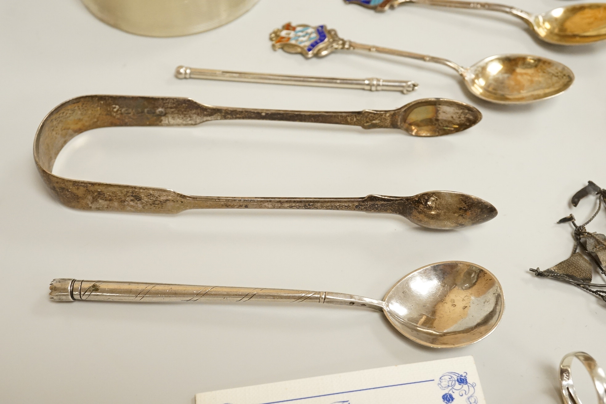Assorted small silver including a mounted ribbed glass match strike, height 40mm, a small Scottish sterling spoon by Hamish Dawson Bowman, 76mm, a pair of George IV silver sugar tongs, commemorative spoons, an early 20th
